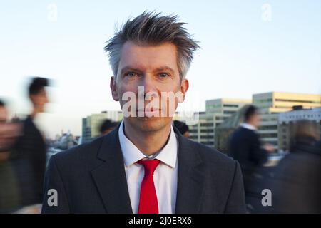 Geschäftsmann steht still, während die Leute hinter sich herlaufen Stockfoto