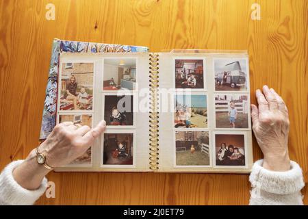 Draufsicht auf eine ältere kaukasische Frau, die ein altes Fotoalbum mit Motiven aus Erinnerungen und Nostalgie betrachtet Stockfoto