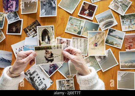 Draufsicht auf eine ältere kaukasische Frau, die sich alte Fotos ansieht Themen von Erinnerungen Nostalgie-Fotos RE Stockfoto