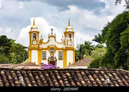 Blick auf die historische Kirche zwischen Dächern und Vegetation in Tiradentes Stadt Stockfoto