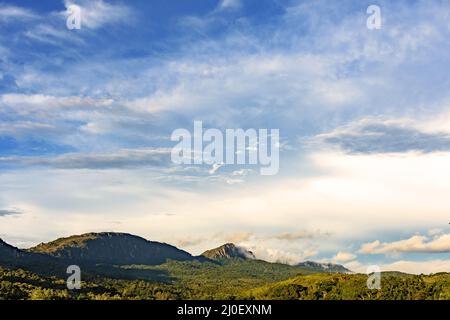 Dämmerung zwischen Wolken, Bergen und Wald Stockfoto