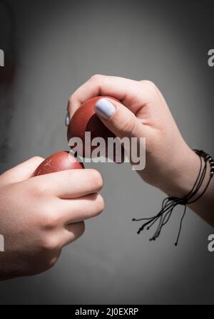 Zwei Menschen schlagen die roten ostereier zusammen. Stockfoto