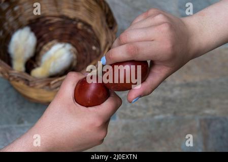 Zwei Menschen schlagen die roten ostereier zusammen. Stockfoto