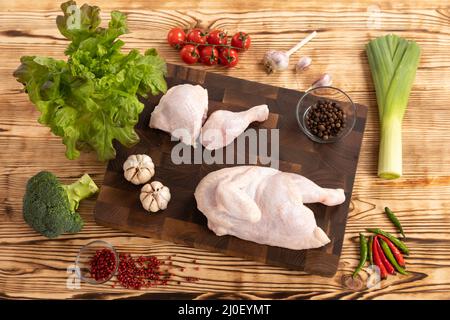 Rohes Huhn und Gemüse auf einem Holzschneidebrett Stockfoto