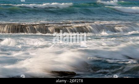 Felsige Küste mit welligem Meer und Wellen, die auf die Felsen krachen, Limassol, Zypern Stockfoto