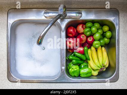 Gemüse und Obst auf einem Singen mit fließendem Wasser und Seife waschen Stockfoto
