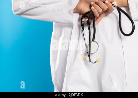 Rückansicht, während die Hände einer jungen Ärztin ein Stethoskop in der Hand halten. Stockfoto
