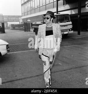 Elton John stellte sich vor, wie er von Los Angeles aus am Flughafen Heathrow ankam. Er ist nach Hause gekommen, um Watford heute Abend ein Spiel spielen zu sehen und wird morgen nach Los Angeles zurückkehren. Er sagte: "Ich muss verrückt sein, so weit zu fliegen, um ein Spiel zu sehen, das beschlagen wird". 26.. Februar 1980. Stockfoto