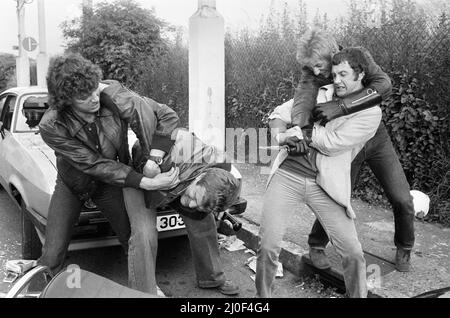 Martin Shaw und Lewis Collins ringen mit den bösen Jungs am Set der Fernsehserie Detective The Professionals. Im Hintergrund ist ihr Ford Capri mit zerschmettert. Juni 1979. Stockfoto