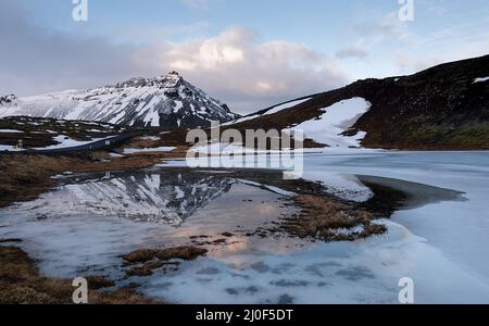 Isländische Berglandschaft, mit schneebedecktem Berg und gefrorenem See Island Stockfoto