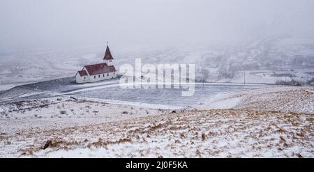 Die Kirche Vik i Myrdal auf dem Gipfel des Hügels bietet malerische Bilder des atlantischen Ozeans A Stockfoto