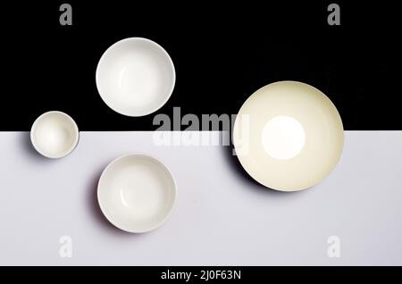 Gruppe von leeren Keramikschalen auf einer schwarzen und weißen Oberfläche Stockfoto