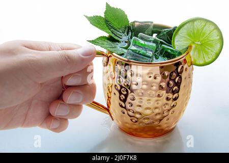 Eine Person, die einen Moskauer Mule Becher auf weißem Hintergrund trinkt Stockfoto