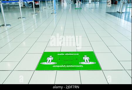 Warnschild auf dem Boden eines Flughafenterminals, um Abstand zum Schutz vor Corona zu sichern Stockfoto