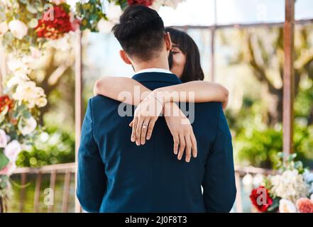Der Bräutigam ist ihr zum Glätten. Eine kurze Aufnahme einer anhänglichen jungen Braut, die ihren Bräutigam küsst, während ihre Hände an ihrem Hochzeitstag um ihn gewickelt sind Stockfoto
