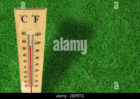 Holzwetterthermometer-Messung an einem heißen Tag auf grünem Gras. Stockfoto