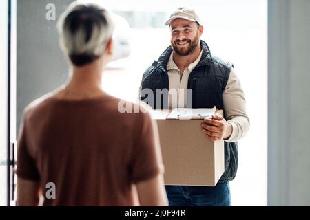 Wir liefern immer pünktlich. Aufnahme eines Kuriers, der eine Lieferung an einen Kunden zu Hause anstellt. Stockfoto