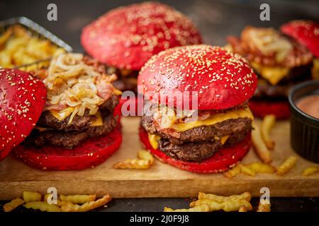 Eine Reihe von roten Brötchen hausgemachte köstliche Burger von Rindfleisch, Speck, Käse, gegrillte Zwiebel auf einem dunklen rostig Stockfoto