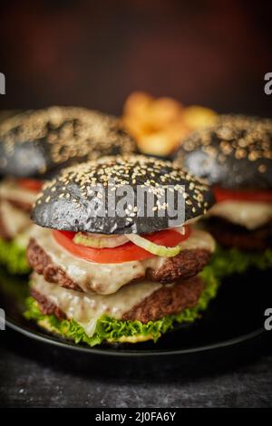 Schwarzer Doppel-Cheeseburger mit Tomaten und Salat Stockfoto