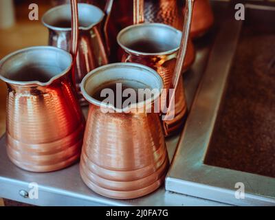 Bronzefarbener metallkaffee türken stehen auf einer Metalloberfläche Stockfoto