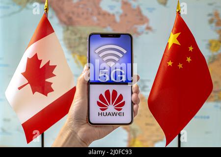 Calgary, Alberta, Kanada. September 8, 2020. Eine Person, die ein iPhone mit einem 5G- und Huawei-Logo auf dem Bildschirm neben einem Canada- und einem C-Logo hält Stockfoto