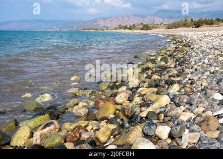 Meereswellen plätschern zu einem felsigen Kiesstrand gegen bewölkten Himmel, Protaras, Cypus Stockfoto