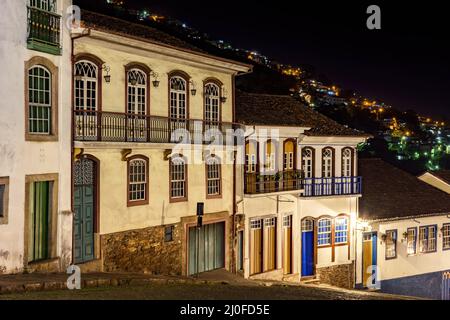 Fassaden von Häusern in Kolonialarchitektur auf einer alten Kopfsteinpflasterstraße, die nachts beleuchtet wird Stockfoto