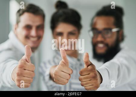 Das Geschäft sah nie besser aus. Porträt einer Gruppe von Geschäftsleuten, die in einem Büro den Daumen nach oben zeigen. Stockfoto