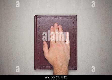 Die Handfläche eines Mannes auf einem Buch Stockfoto