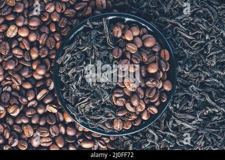 Geröstete Kaffeebohnen und trockene Blätter von schwarzem Tee Stockfoto