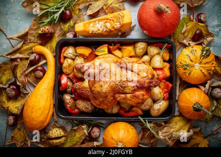 Gebratenes Hähnchen oder pute garniert mit Kürbissen, Pfeffer und Kartoffeln. Serviert auf einem rustikalen Tisch Stockfoto