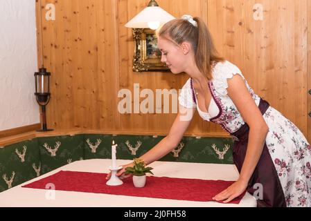 Festlicher Hoteltisch - junge Kellnerin in traditioneller Tracht Stockfoto