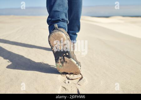 Kein Klima ist zu viel. Aufnahme eines jungen Wanderers, der entlang der Sanddünen läuft. Stockfoto