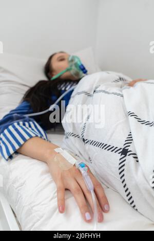 Der Teenager liegt krank in Verbindung mit einem Atemschutzgerät, weil sie Schwierigkeiten beim Atmen hat. Stockfoto