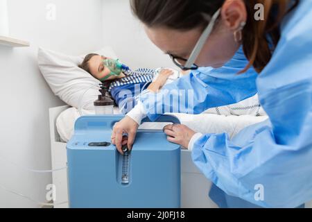 Der Arzt reguliert die Atemschutzmaske so, dass der Patient die richtige Menge an Sauerstoff hat. Stockfoto