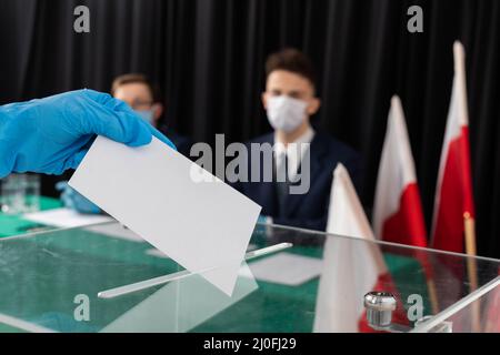 Ein Teenager wirft einen fertigen Wahlausweis in die transparente Wahlurne. Stockfoto