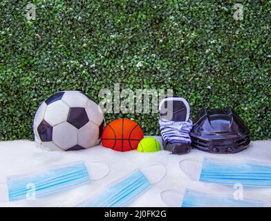 Ein Fußball oder Fußball, Basketball, Tennisball, Schlittschuhe mit Helm auf Schnee mit Gesichtsmasken. Konzept: Sport im Winter Stockfoto