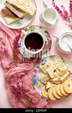 Heiße Schokolade oder Kakao in Tasse mit verschiedenen Süßigkeiten an den Seiten. Weiße Schokoriegel und Kekse Stockfoto
