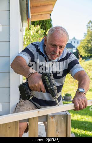 Der Handwerker selbst macht im Garten eine kleine Holzhütte Stockfoto