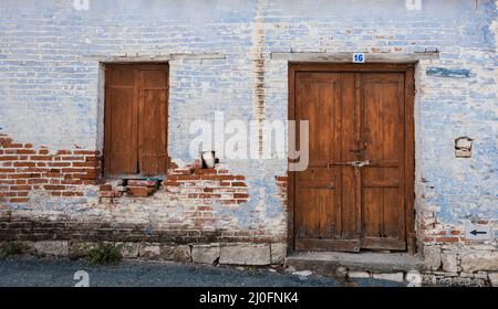 Außenansicht eines alten Dorfhauses mit geschlossener Vitnage-Tür und Fenster. Stockfoto