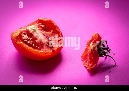 Scheibe verfaultes Gemüse aus roten Tomaten, isoliert auf einem magentafarbenen Hintergrund Stockfoto