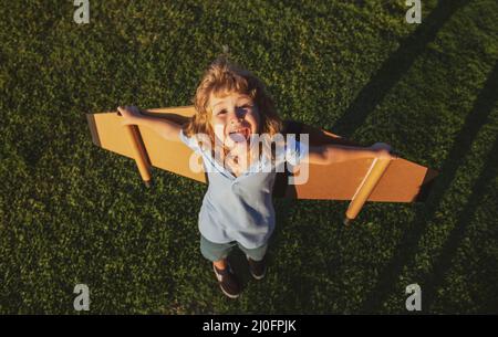 Aufgeregt Kind mit Rucksack Flügel. Kind spielt Flieger und träumt im Park. Lächelndes Kind träumt von Sommerurlaub und Reisen. Junge Stockfoto