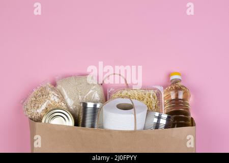 Papiertüte mit Lebensmittelkrisen für die Zeit der Quarantäneisolation auf rosa Hintergrund mit Cop Stockfoto