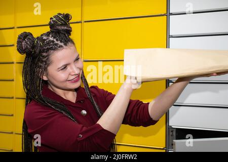 Ein junges Mädchen schaut mit Interesse und Freude auf das Paket, das gerade angekommen ist. Sie erhielt eine unerwartete Mail. Stockfoto