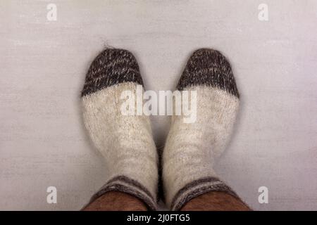 Herrenfüße in weißen Stricksocken aus Wolle aus nächster Nähe Stockfoto