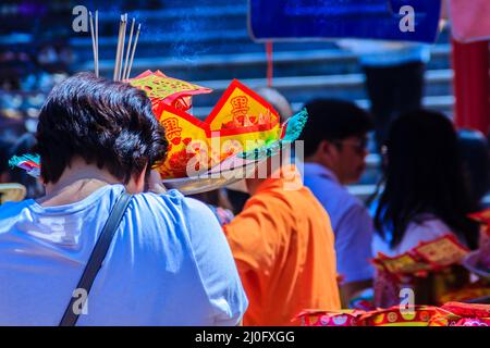 Menschen mit Papiergeld, Papiergold und Brandscherz halten sich am chinesischen Schrein, weil sie Verdienste verdient haben und Gott im Chinesischen Neuen Respekt erweisen Stockfoto