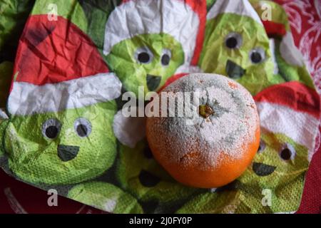Schimmelige Mandarine und zerknitterte Serviette Stockfoto