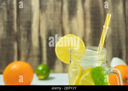 Frische Zitruslimonade mit Minze auf rustikalem Hintergrund. Limonade und Zutaten auf Holzhintergrund, Kopierraum. Sommerlimonade mit Limette und Minze Stockfoto