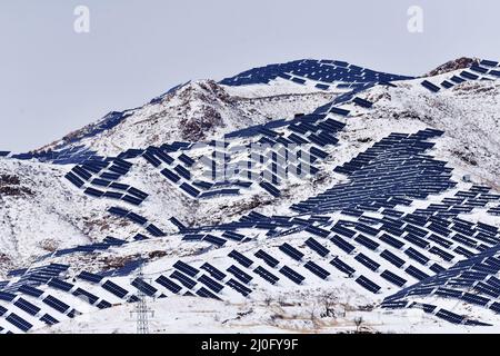 ZHANGJIAKOU, CHINA - 19. MÄRZ 2022 - Ein Photovoltaikkraftwerk wird nach Schnee auf kargen Hügeln in Zhangjiakou, Provinz Hebei, am 19. März 2022 gesehen. Stockfoto