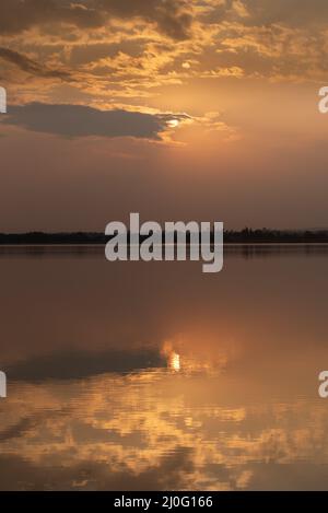 Sonnenuntergang mit Wolken am Himmel auf dem Wasser reflektiert Stockfoto